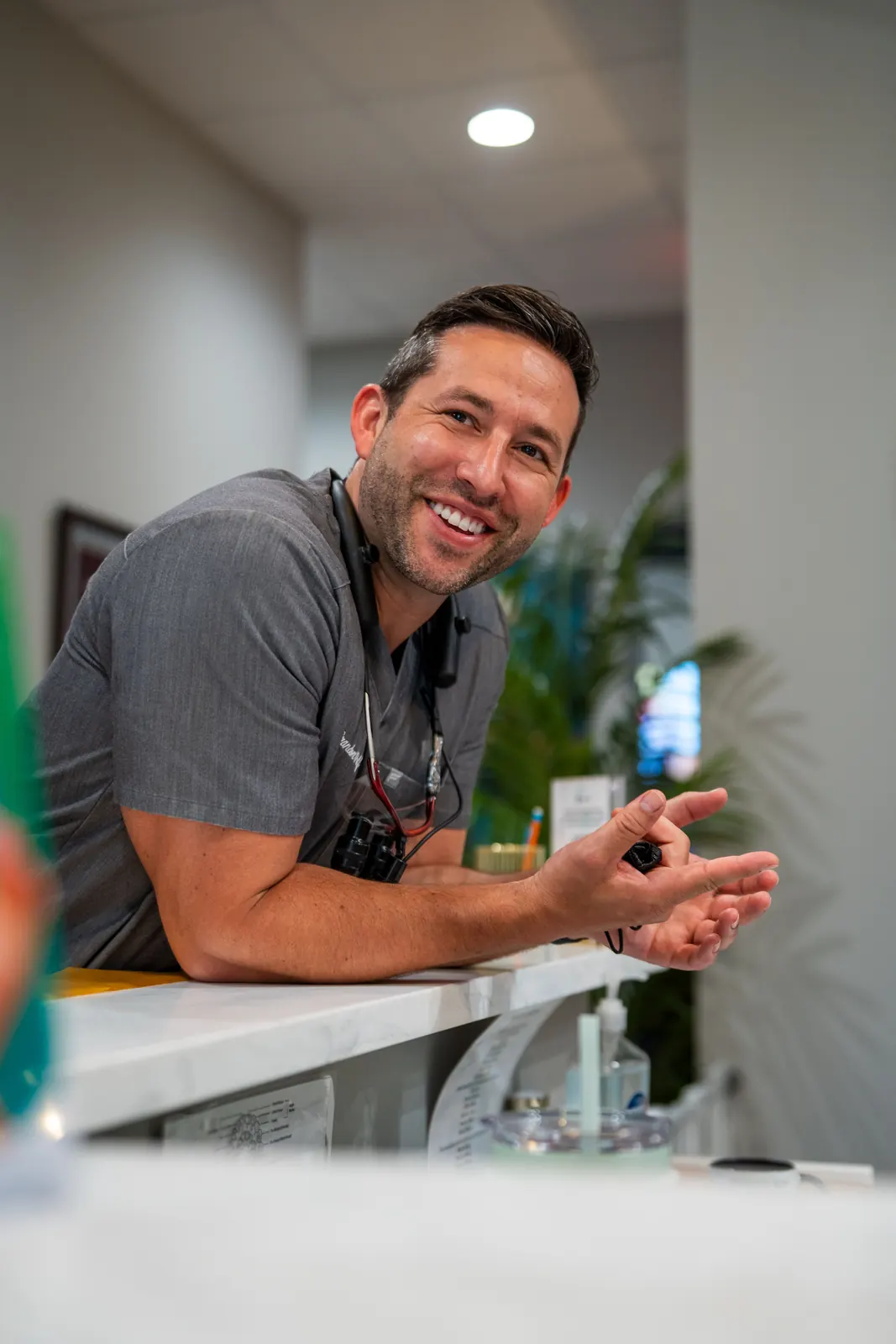 Dr. Brandon Wolf smiling and chatting with a patient at the front desk of Illumination Dentistry in Lutz, FL