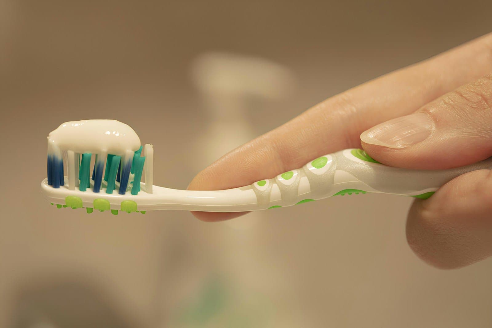A hand holding a toothbrush with toothpaste on the bristles