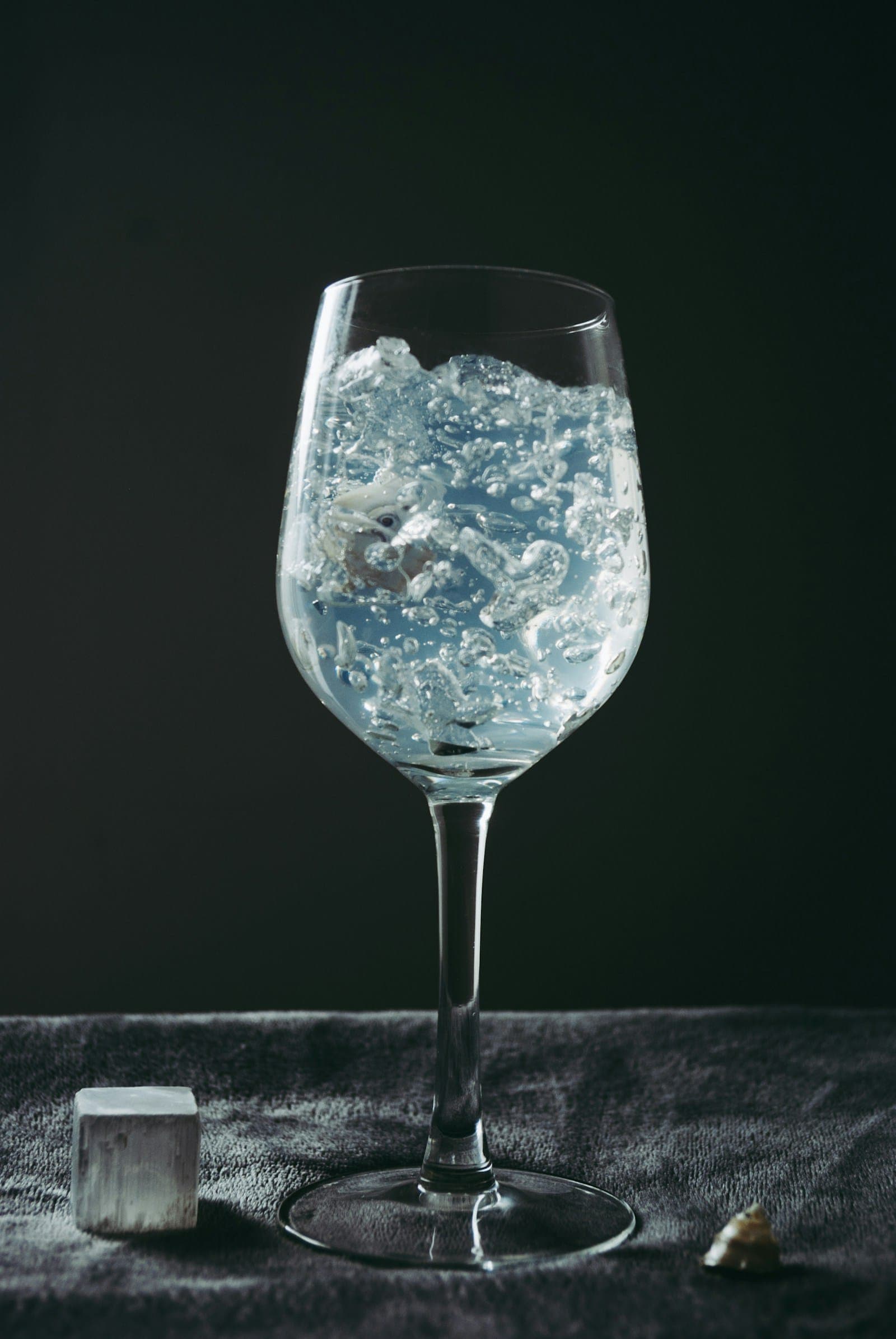 A glass filled with ice water against a dark background